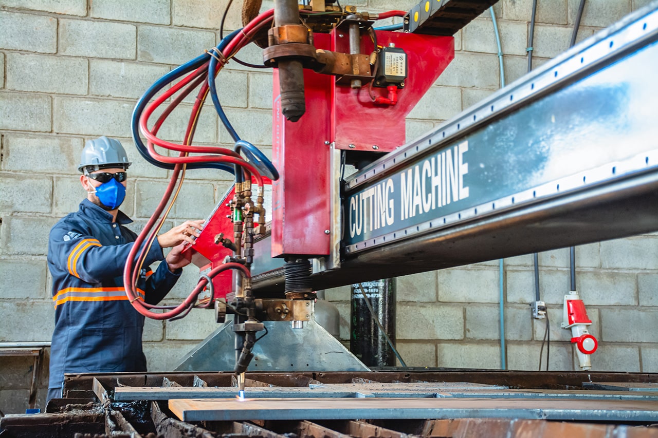 Operador controlando máquina CNC para corte de perfis metálicos